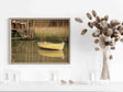 Detailed view of a framed art print depicting a boat on a river amidst fall foliage - MRC Art by Design